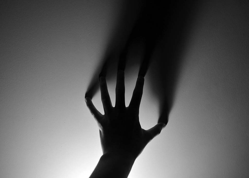 Hand against a wall casting a shadow upward