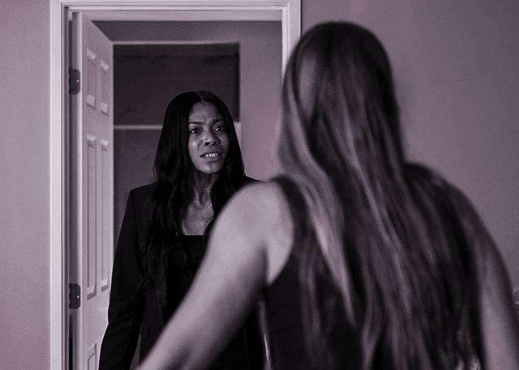Two women standing in a doorway, facing each other and arguing.